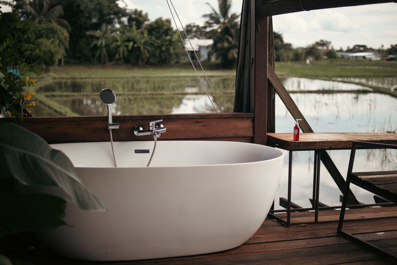 Relaxing outdoor bathtub setup with a scenic view of rice fields and lush greenery.